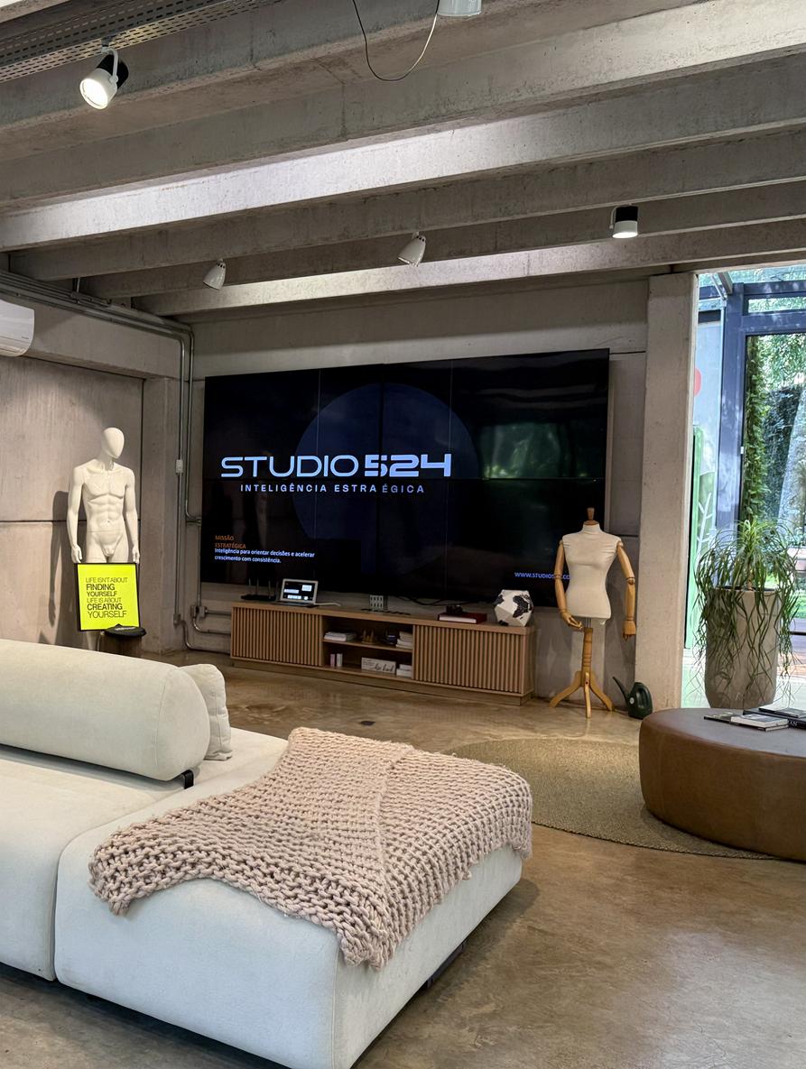 Modern living room with a beige sectional sofa, black low coffee table, large abstract wall art, and a floor-to-ceiling window with curtains.